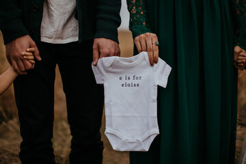 couple holding a onesie