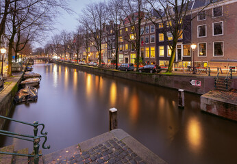 Beautiful old houses on the city waterfront of Amsterdam at sunset.
