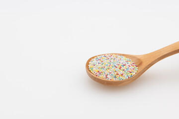 Cuchara de madera con coloridas bolas dulces de caramelo para decorar pasteles, aislado en blanco