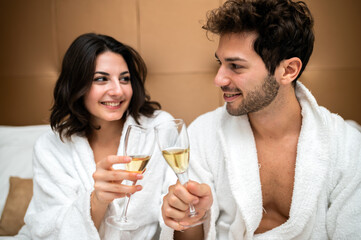 Cheerful couple in bathrobe toasting champagne glasses