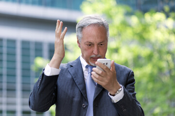 Angry businessman looking at his cellphone