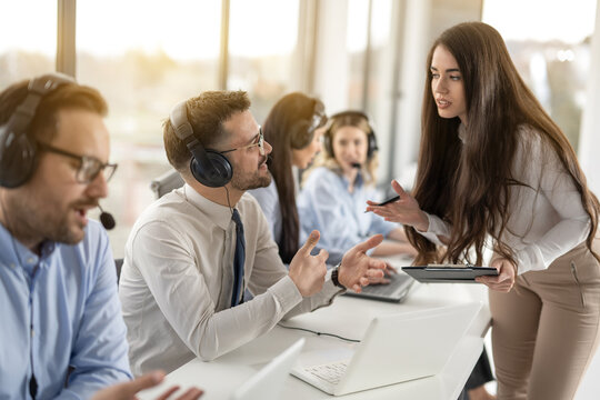 Attractive businesswoman supervisor training work to her multi-ethnic colleagues in call center office