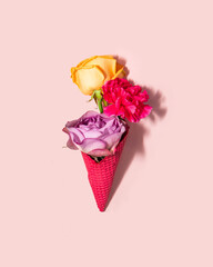 Pastel flowers in ice cream cone on light pink background. Creative food concept. Minimalistic nature composition. Sunny summer day idea. 8th march idea.