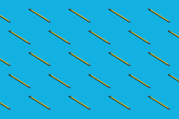 Rows of sharpened yellow pencils on a bright blue background