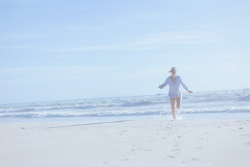 Full length portrait of smiling elegant woman at beach running