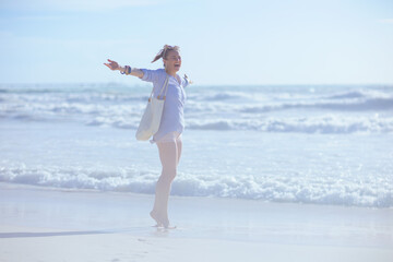 Full length portrait of smiling modern female rejoicing at beach