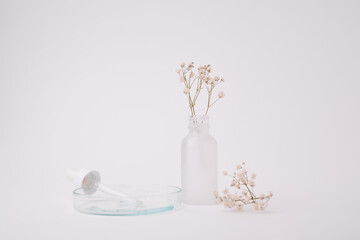 Fototapeta na wymiar Glass skincare bottle with flower top view for self-care and wellness concept.