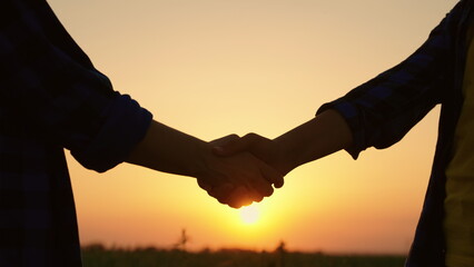 Business people shake hands with each other outdoors in field. Agriculture business, agricultural...