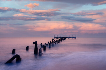 The old pier is in a decayed condition in the morning light.