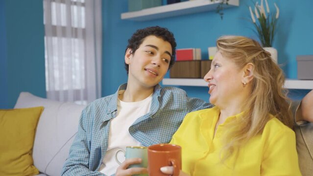 Cheerful and delightful mother and son.
Happy mother and son sitting on sofa at home and chatting.
