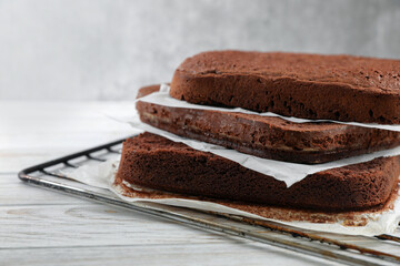 Layers of homemade chocolate sponge cake on white wooden table, closeup