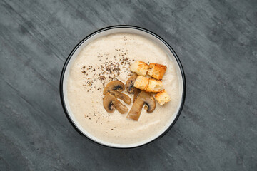 Delicious cream soup with mushrooms and croutons on black table, top view
