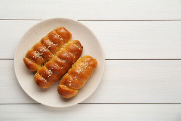 Delicious sausage rolls on white wooden table, top view. Space for text