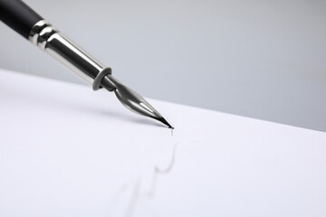 Signing on sheet of paper with fountain pen against light grey background, closeup. Space for text