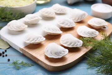 Fototapeta na wymiar Raw dumplings (varenyky) and ingredients on light blue table, closeup