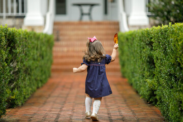 A little girl running down a brick walkway path