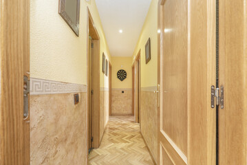 Distribution corridors of an empty house with light oak flooring laid in a herringbone pattern, two-tone walls and oak door joinery and trim