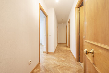 Distribution corridors of a house with light oak flooring laid in a herringbone pattern, white walls with gotelet and oak woodwork on the doors and baseboards