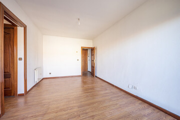Empty living room with floating oak flooring, access doors to other rooms in varnished sapele, white painted walls and white aluminum radiator