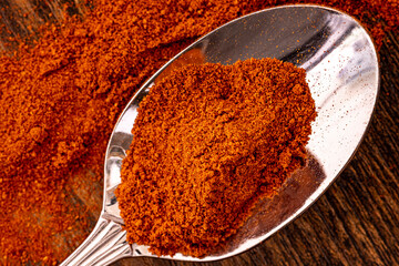 A metal spoon full of spicy paprika