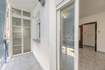 Narrow terrace with stoneware floors, aluminum and glass wardrobe and access door to the living...