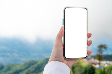 Women using a smartphone with empty white screen at the outdoor with mountain view and sky at the...