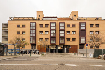 facade of a modern residential building built with light bricks and red metal framing