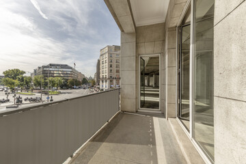 Terrace of an office with a gray granite facade with large doors and windows of white aluminum and glass and views of a square with little traffic