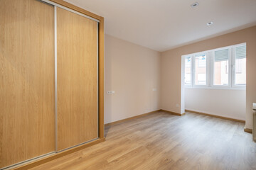 An empty room with a pomegranate terrace for the living space with a white aluminum window and a built-in wardrobe with sliding oak doors