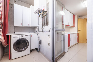 utility room with a kitchen with a washing machine, storage units and a natural gas boiler