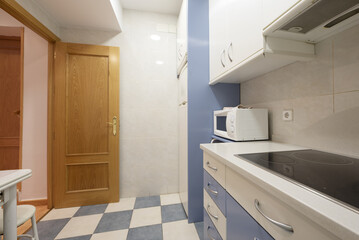 Fototapeta na wymiar apartment kitchen with white and blue cabinets to match the tiles and oak wood door
