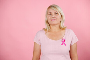 Woman does self-exam for breast cancer prevention wearing pink t-shirt and color background - obrazy, fototapety, plakaty