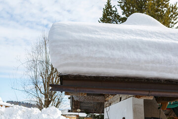 A huge amount of snow on a roof of a house in winter outdoors