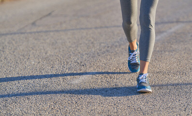 legs of sporty woman walking on the road