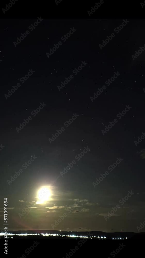 Wall mural time-lapse of the moon rising with stars the stars around it in the sky with clouds