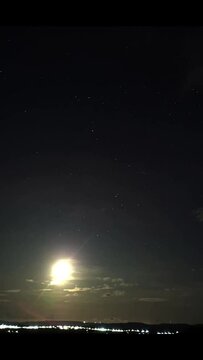time-lapse of the moon rising with stars the stars around it in the sky with clouds