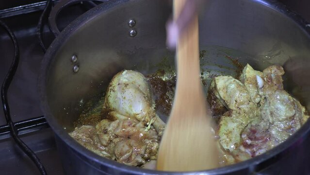 Stirring chicken in spices preparing the filing for a roti