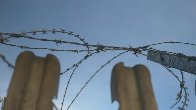 Barbed Wire Fence Looking Up on to Blue Sky Pan