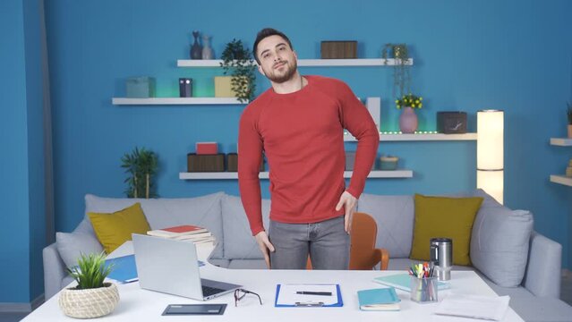 Man doing relaxing stretching exercises in modern home office. He relaxes by doing standing waist exercises.dern home office shows the camera how to do the standing waist exercis