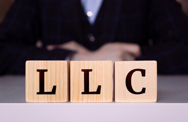 The word "LLC" written on wood cube. LLC - short for Limited Liability Company