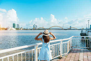 Woman Traveler with blue dress visiting in Da Nang city. Tourist sightseeing the river view with...