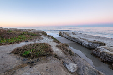 Rocky shoreline points out to sea at Windansea beach in San Diego, California.