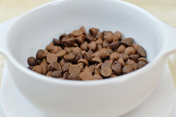 Chocolate chips in white bowl. Measuring cake ingredients