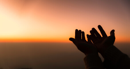Silhouette of woman hands praying for worship God at sky background. Christians pray to jesus christ for calmness. In morning people got to a quiet place and prayed. Banner with copy space. - obrazy, fototapety, plakaty