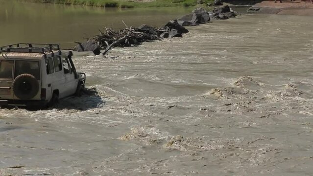 Jeep drives across Cahills Crossing in Australia as crocodiles wait just downstream.
