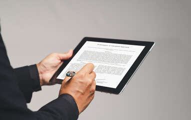 Businessman hands an electronic signature on a tablet while standing on a gray background in the...