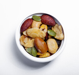 Nut mix in small white plate. Nuts - pecans, macadamias, Brazil nuts, walnuts, almonds, hazelnuts, pistachios, cashews, peanuts. Upper view.