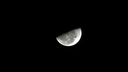Moon, close-up shot. A half moon. Lunar context. Moonlight. A bright moon. Moon craters. Moon in the sky. 