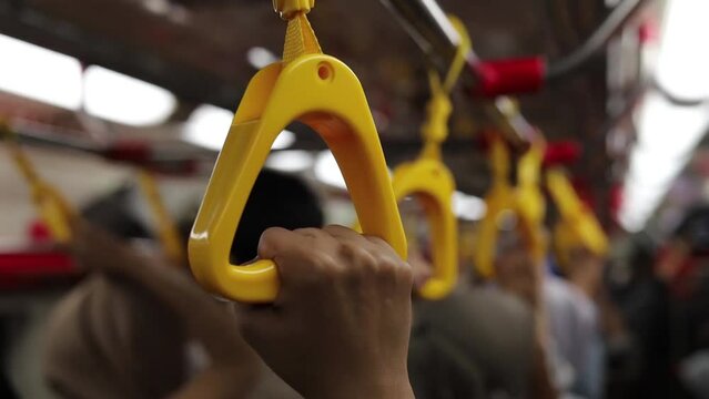Closeup woman traveler grab handrail support, handle and transportation ring in crowded cabin for journey