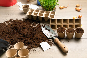Garden tools with fertile black soil with shovel and cardboard pot for seeds. Spring planting time.